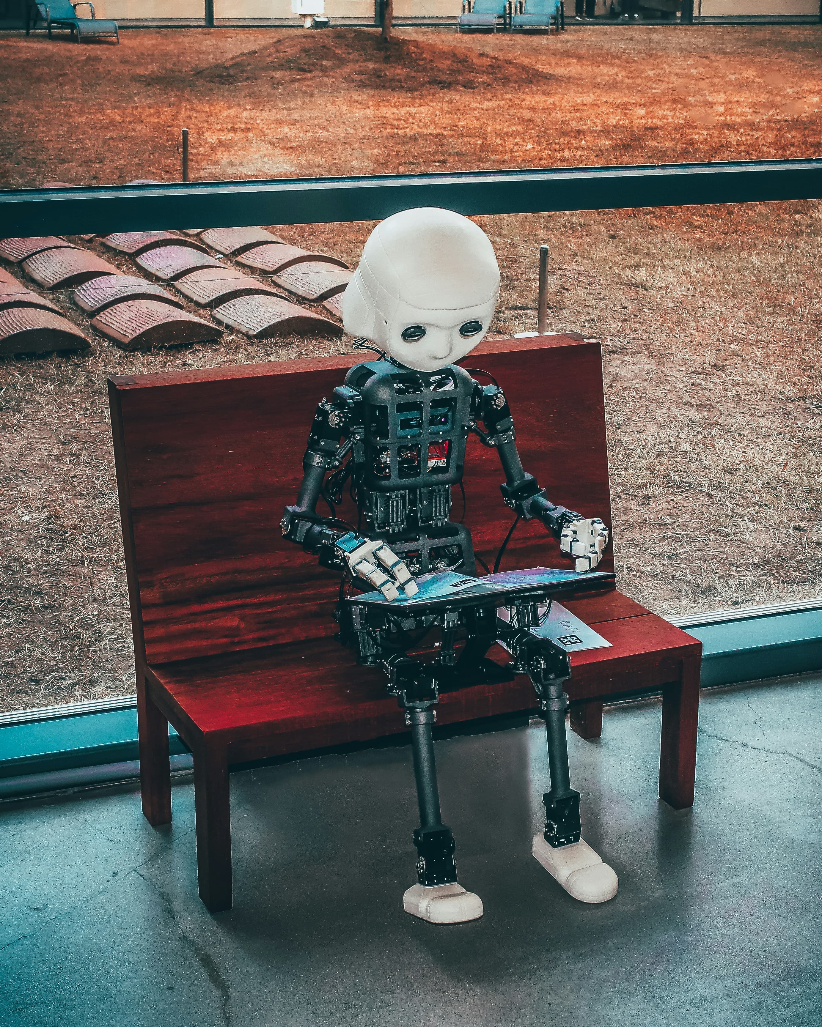 Humanoid robot reviewing a tablet on a bench, representing an enterprise AI assistant